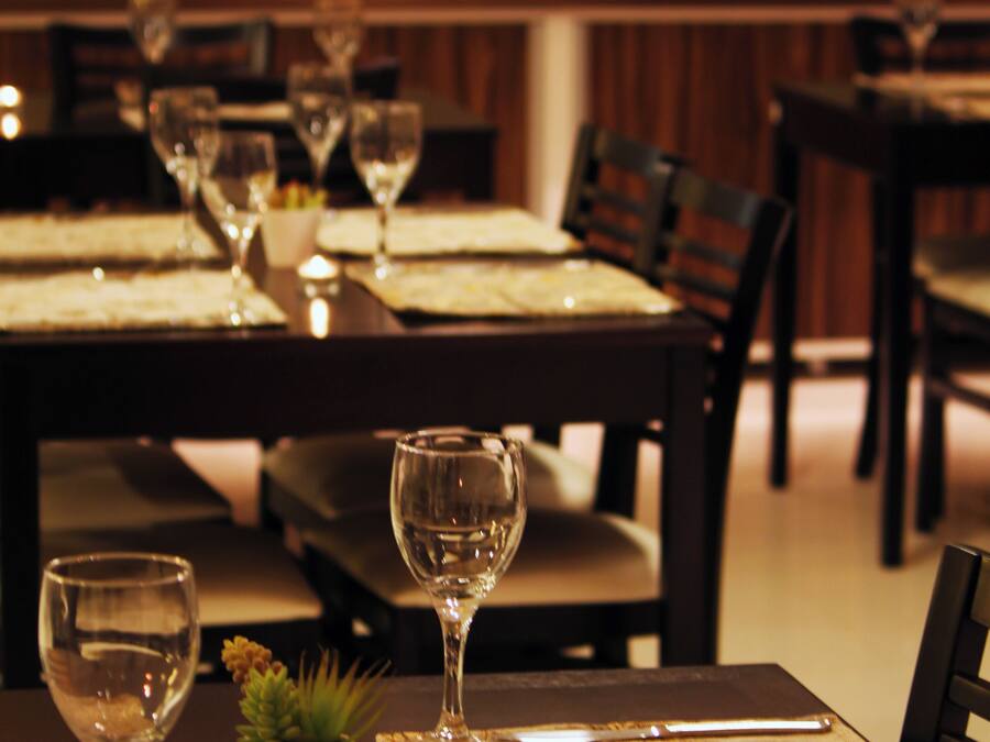 A dining table set with wine glasses, plates, and a candle.