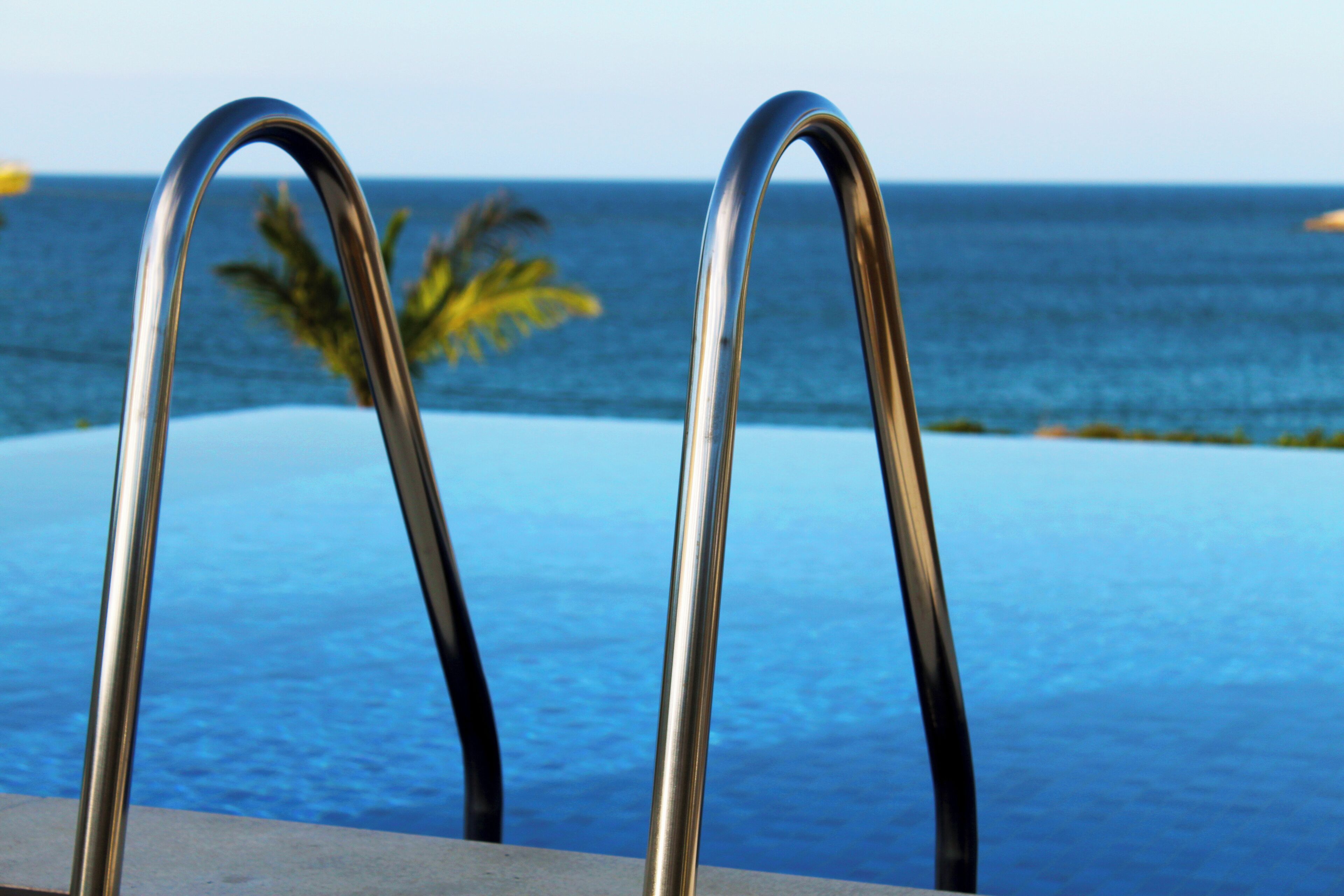 Ein Pool mit Metallgeländern und Blick aufs Meer.