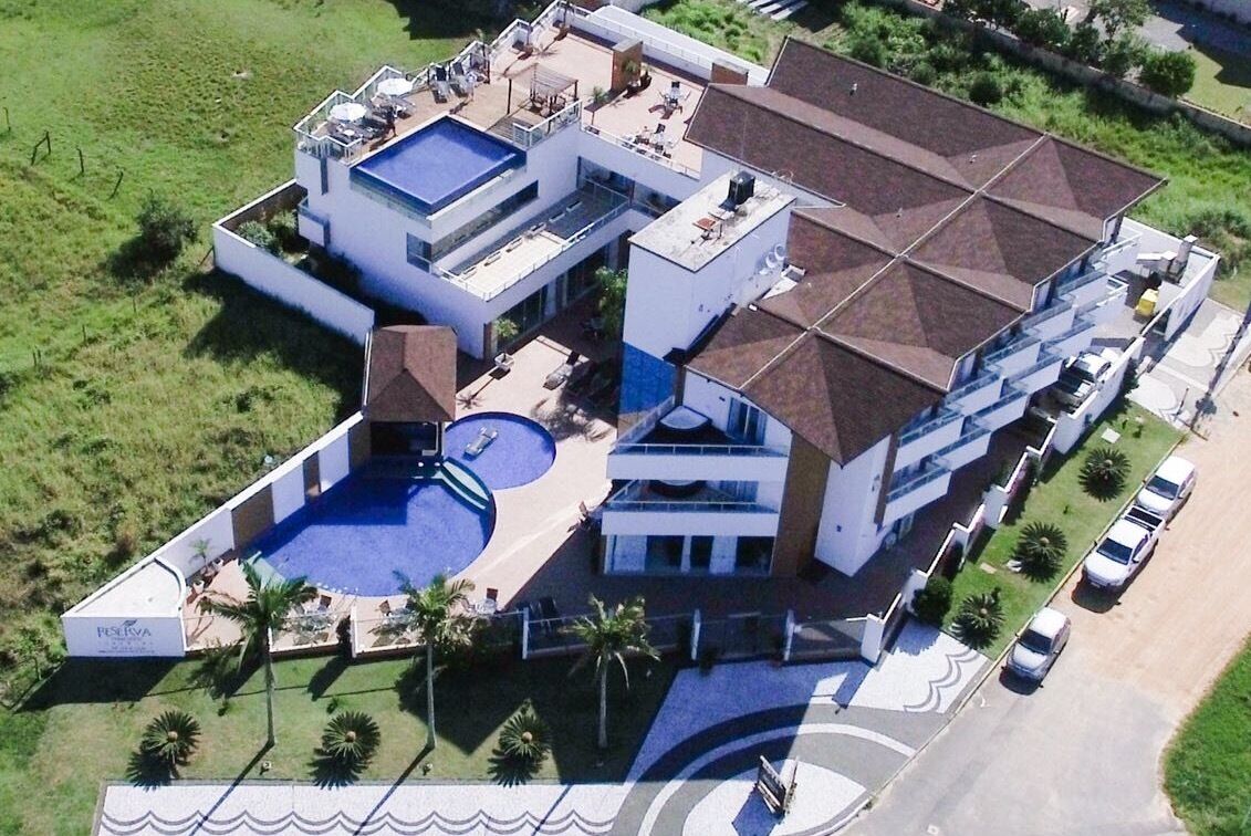 A modern multi-story building with a rooftop pool, a covered outdoor area, and a parking lot.