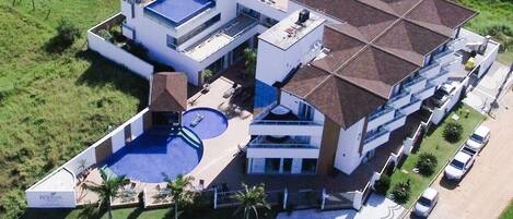 Un immeuble moderne à plusieurs étages, doté d’une piscine sur le toit, d’un espace extérieur couvert et d’un parking.