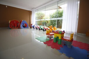 Una habitación amplia con ventanas grandes, una zona de juegos con juguetes coloridos y vistas despejadas al exterior.