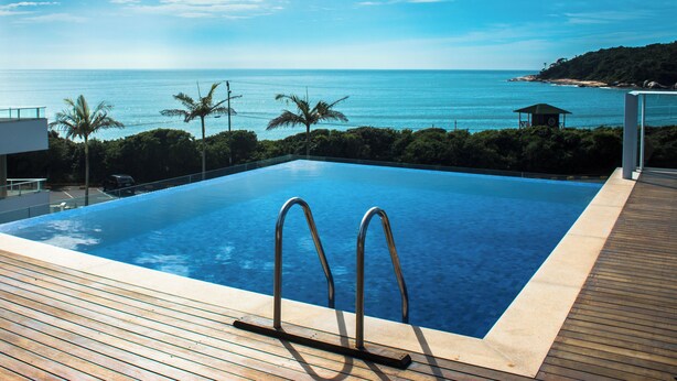 Una piscina con vista al océano y palmeras.