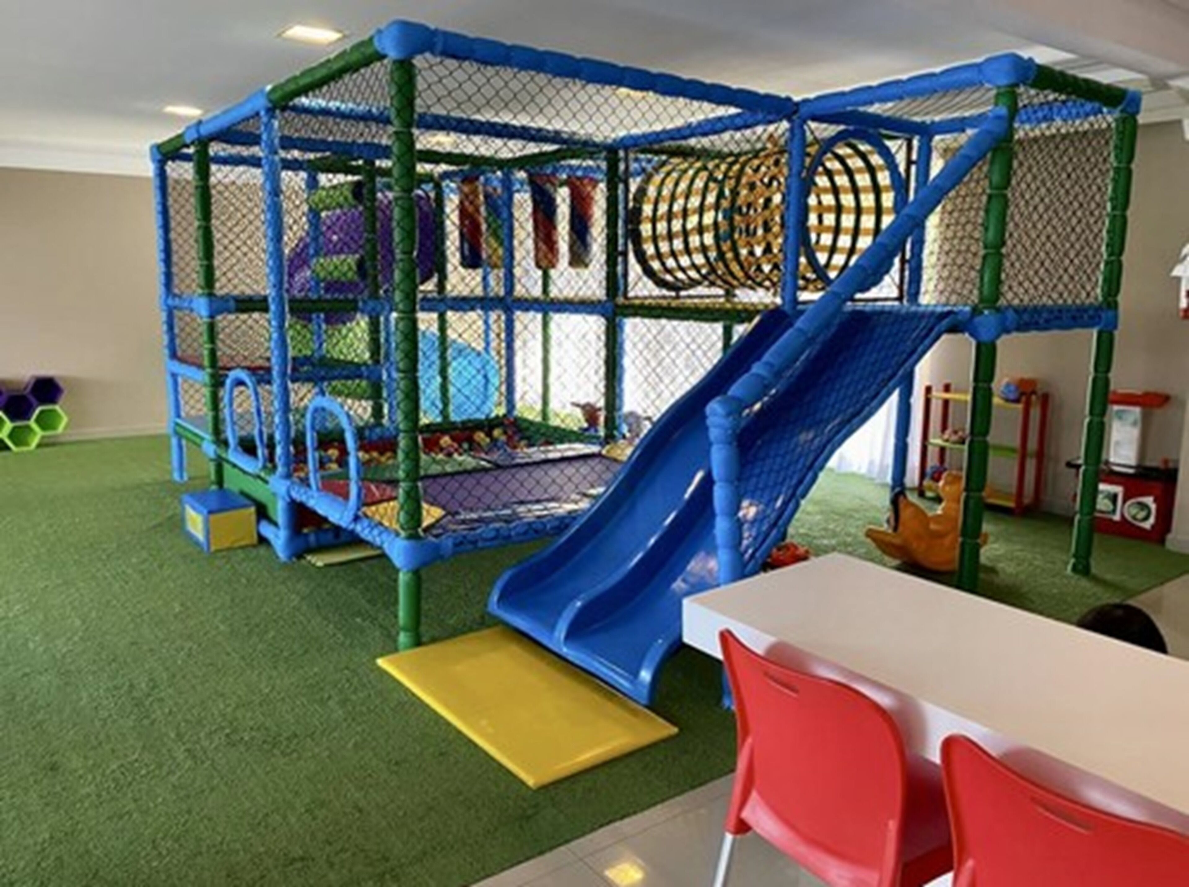 A children's play area with a slide, climbing net, and various play structures.