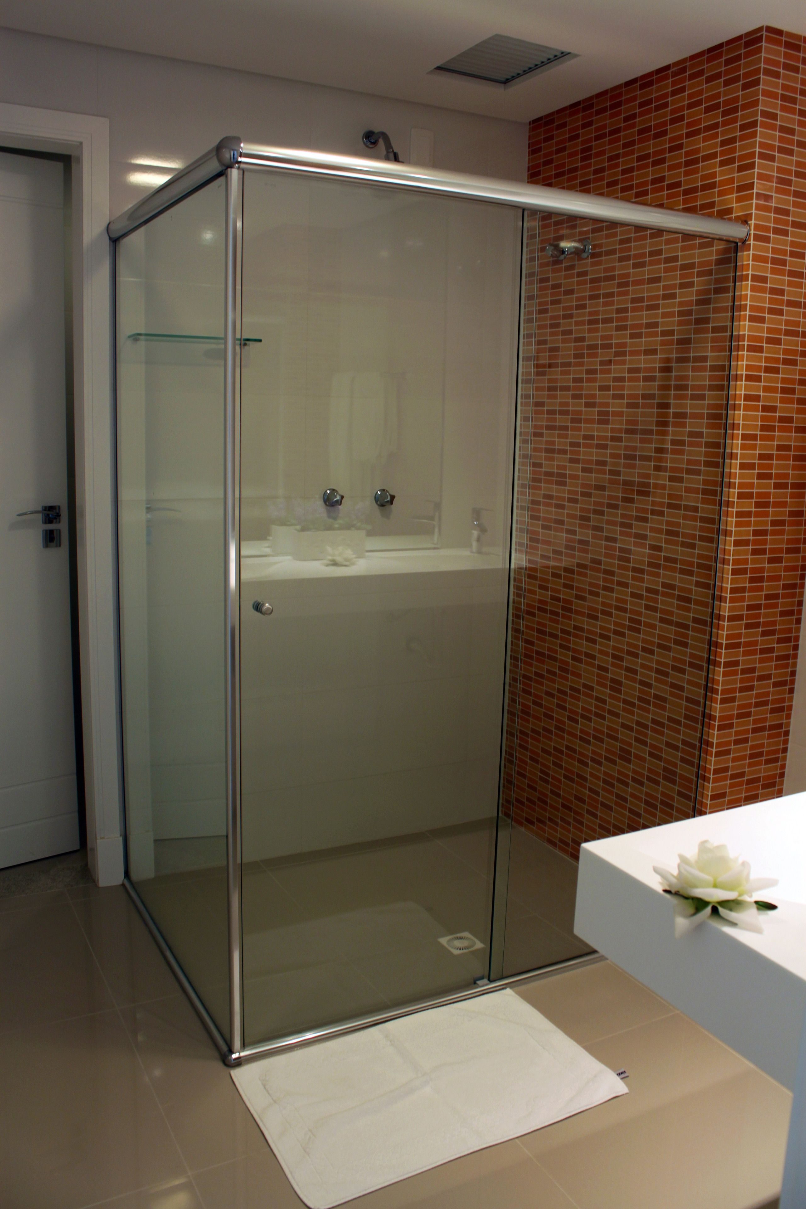 Un baño moderno con ducha acristalada, lavabo blanco y pared con azulejos.