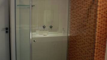 Un baño moderno con ducha acristalada, lavabo blanco y pared con azulejos.