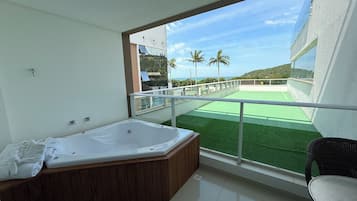 Un balcón con jacuzzi, vistas al mar y zona ajardinada.