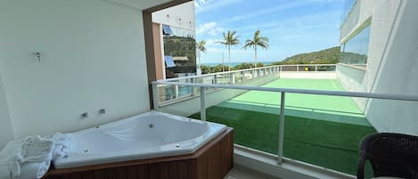 Un balcone con idromassaggio, vista sul mare e una zona verde.