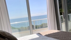 Un dormitorio con un ventanal que ofrece vistas a la costa.