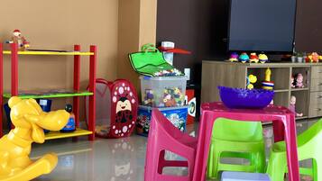 Un espace de jeux avec des jouets en plastique de couleurs vives, une télévision et un meuble de rangement.