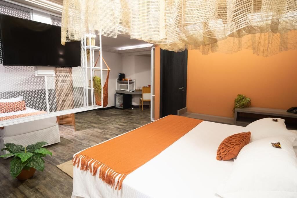 Habitación de hotel moderna con cama, televisor y una zona de estar acogedora.