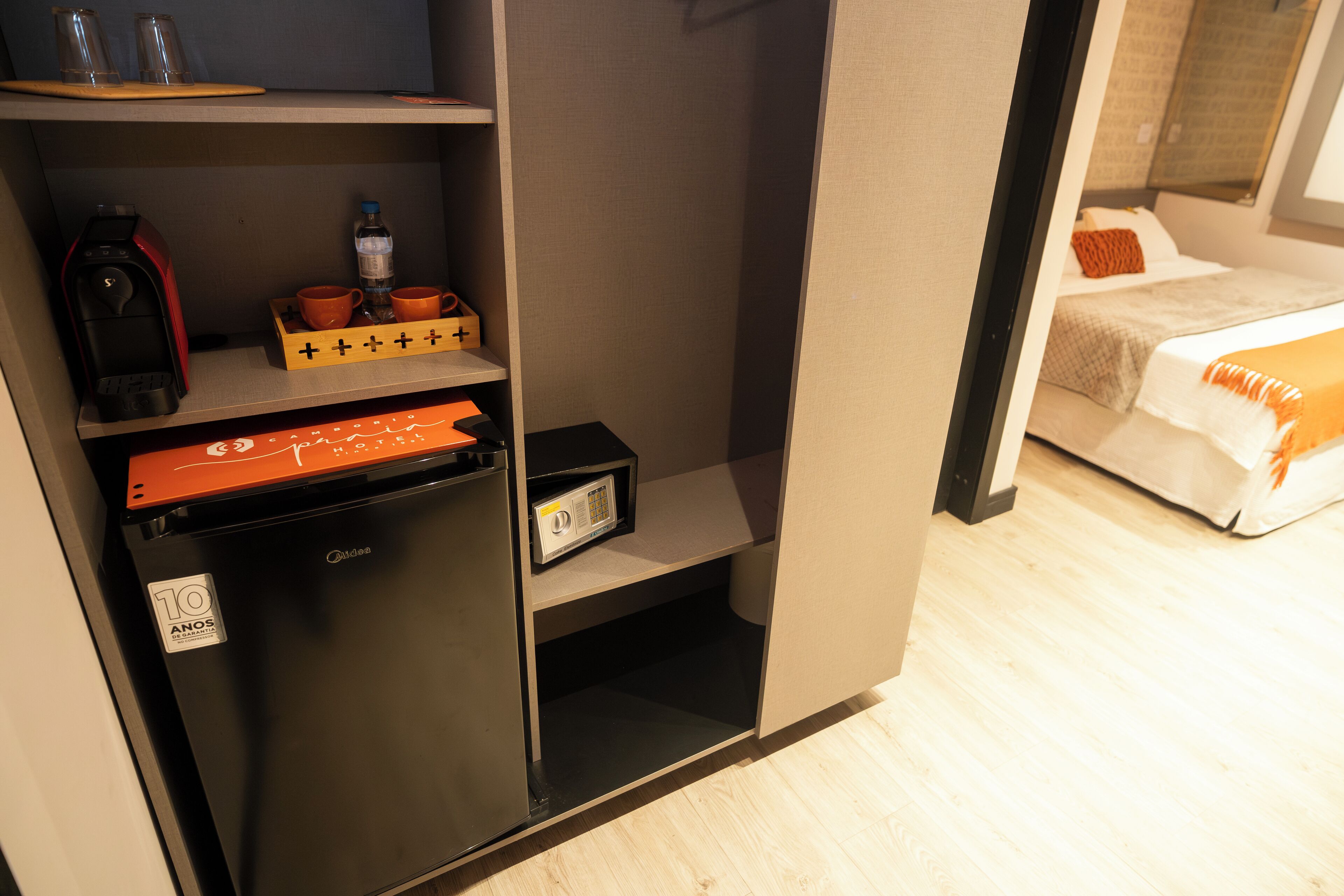 Habitación de hotel pequeña con kitchenette, cama y una zona de estar.
