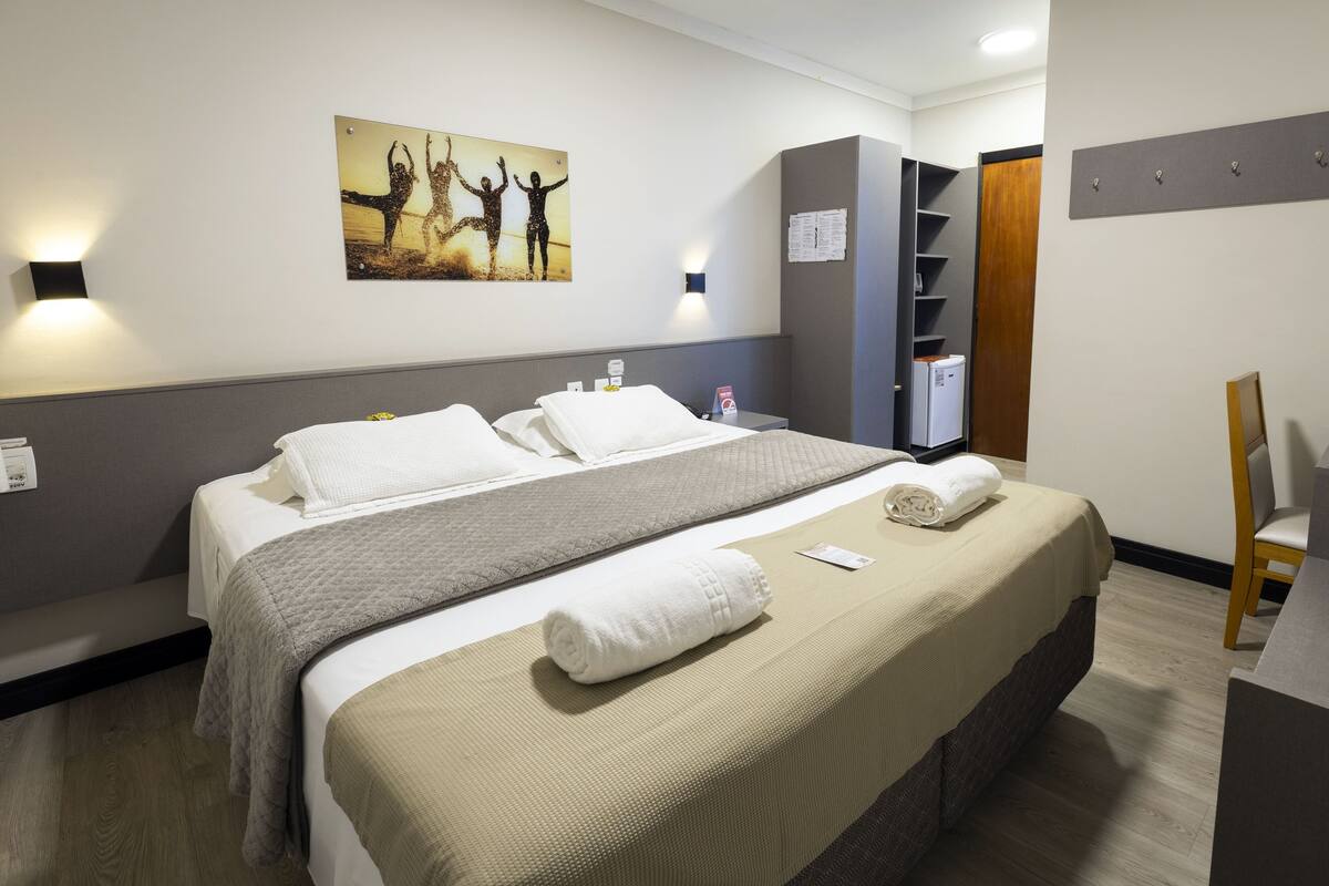 Ein Hotelzimmer mit Bett, einem Gemälde, einem Kleiderschrank und einem Schreibtisch.