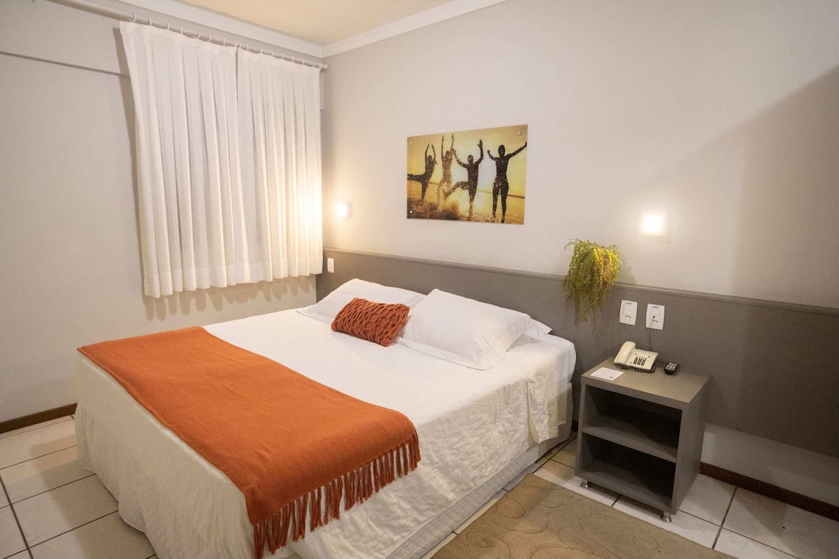 Ein Hotelzimmer mit Bett, Nachttisch, Telefon und einem Wandbild.
