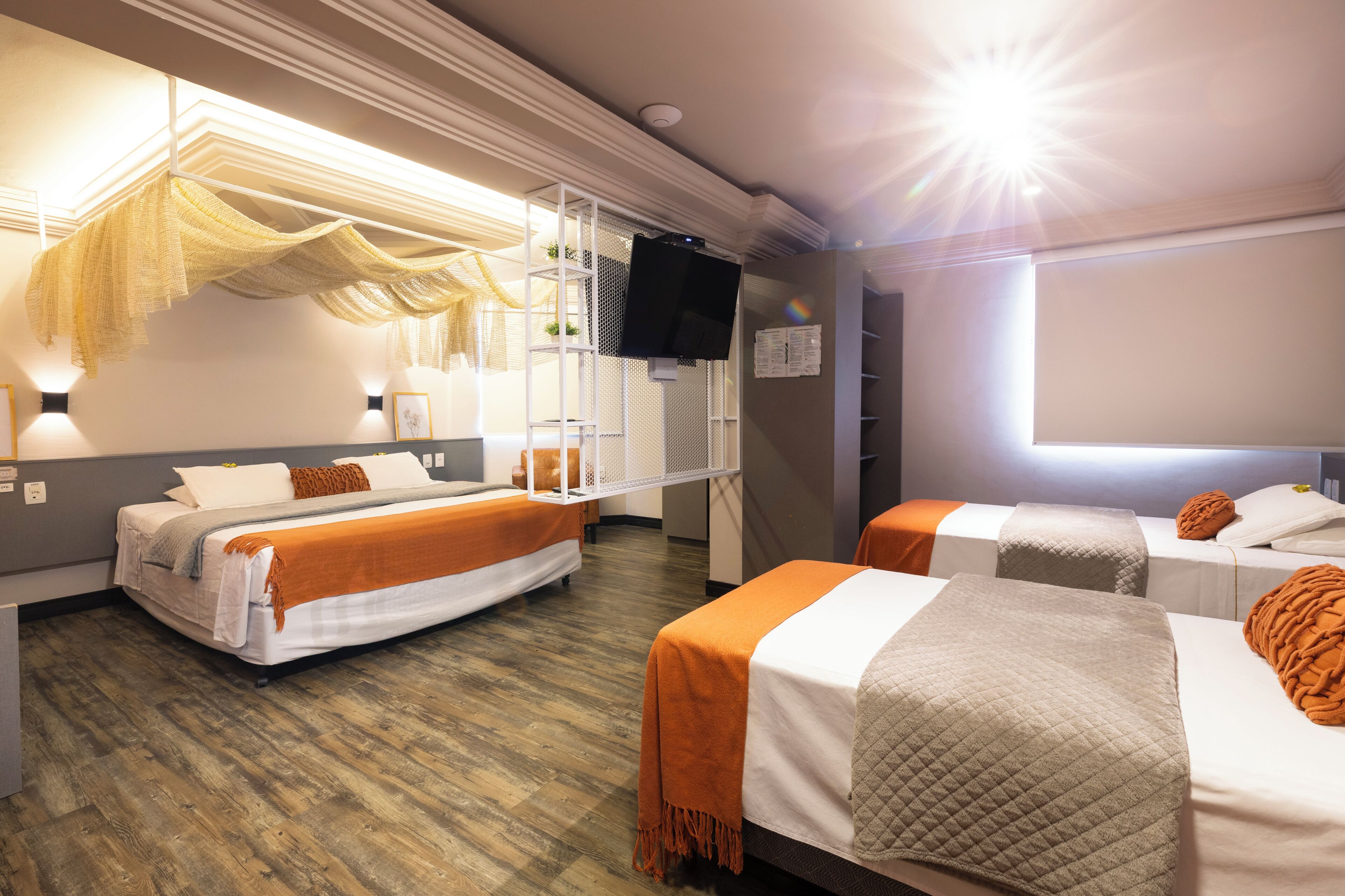 A hotel room with two beds, a TV, a window, and a ceiling light.