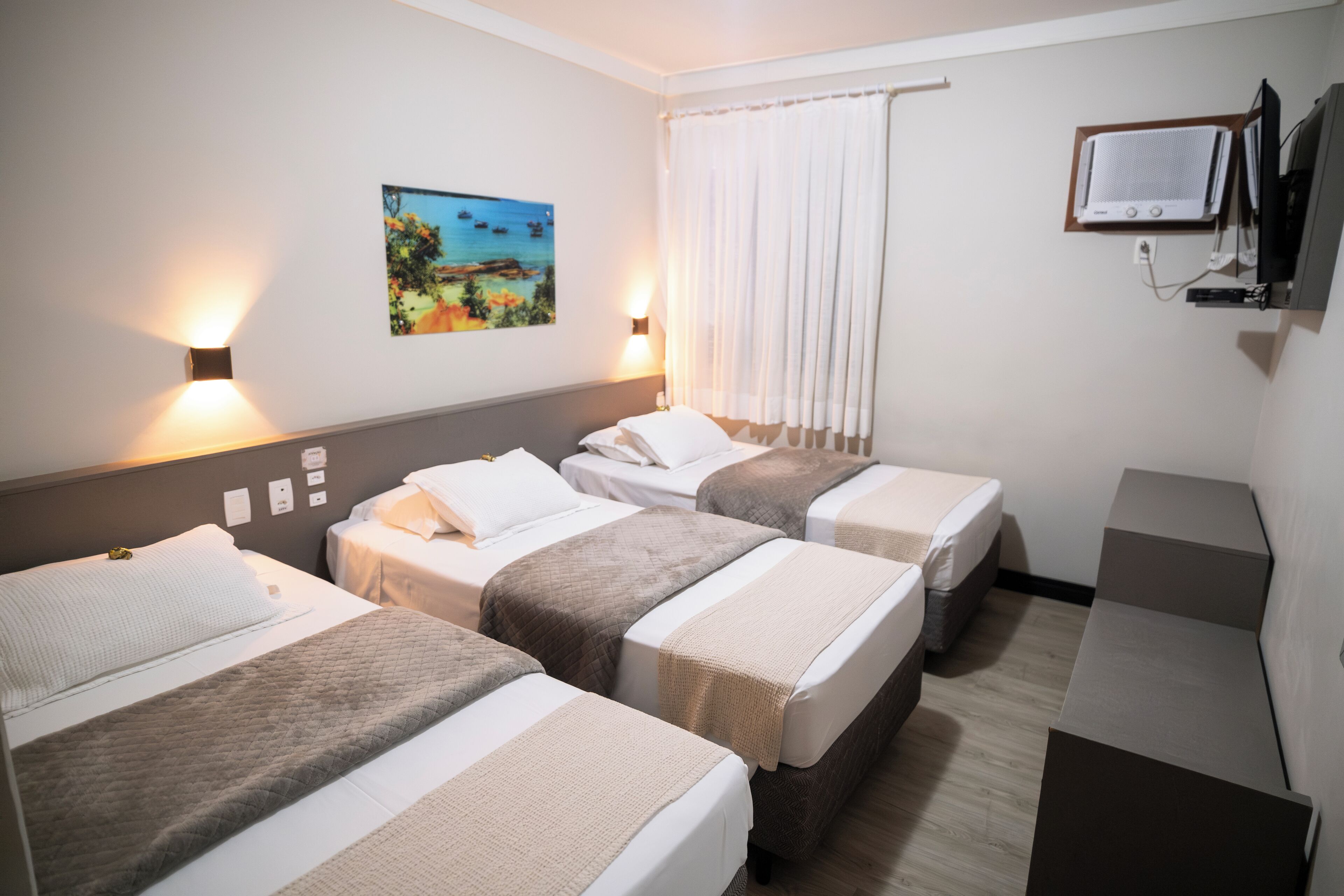 Hotellihuone, jossa on kaksi sänkyä, seinälle asennettu taulutelevisio ja seinällä taulu.