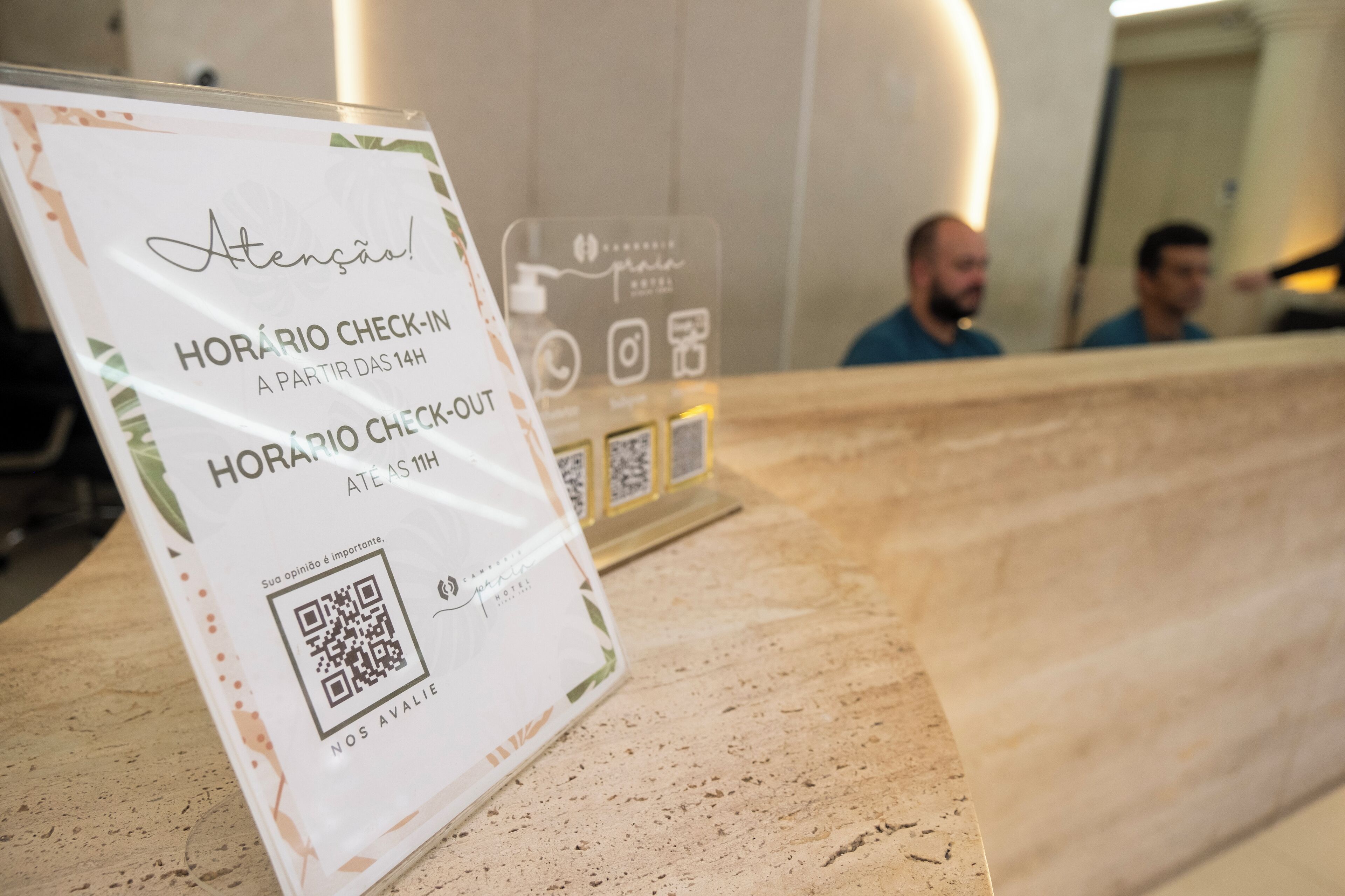 A hotel reception desk with a sign indicating check-in and check-out times.