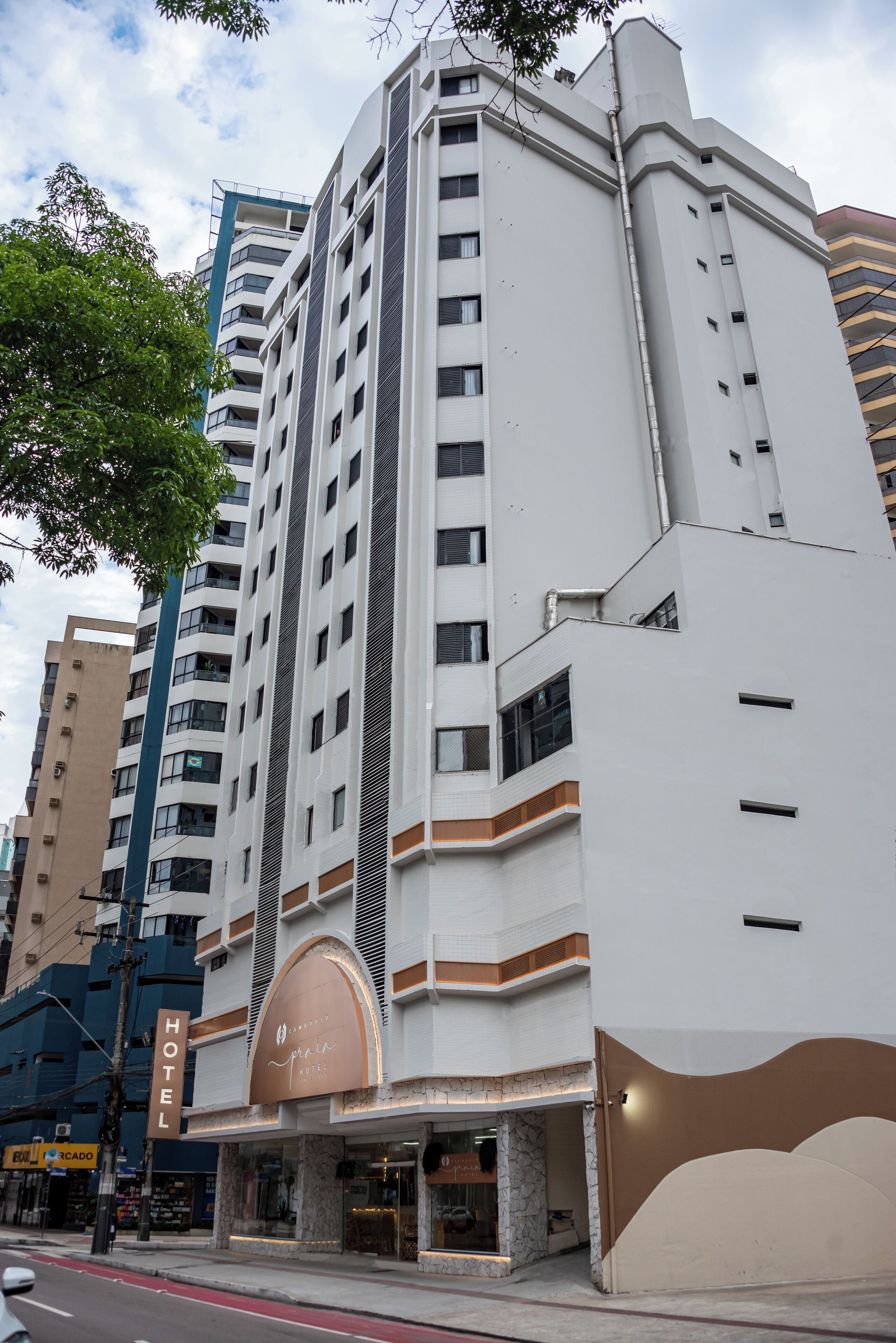 A modern hotel with a prominent entrance, multiple floors, and a clear sky.