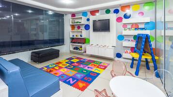 Children can play and learn in this spacious room with a large TV, alphabet play mat, and toy-filled shelves.