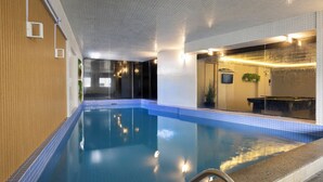 Une piscine intérieure à l’eau claire, avec un mur en bois d’un côté et un mur carrelé de l’autre.