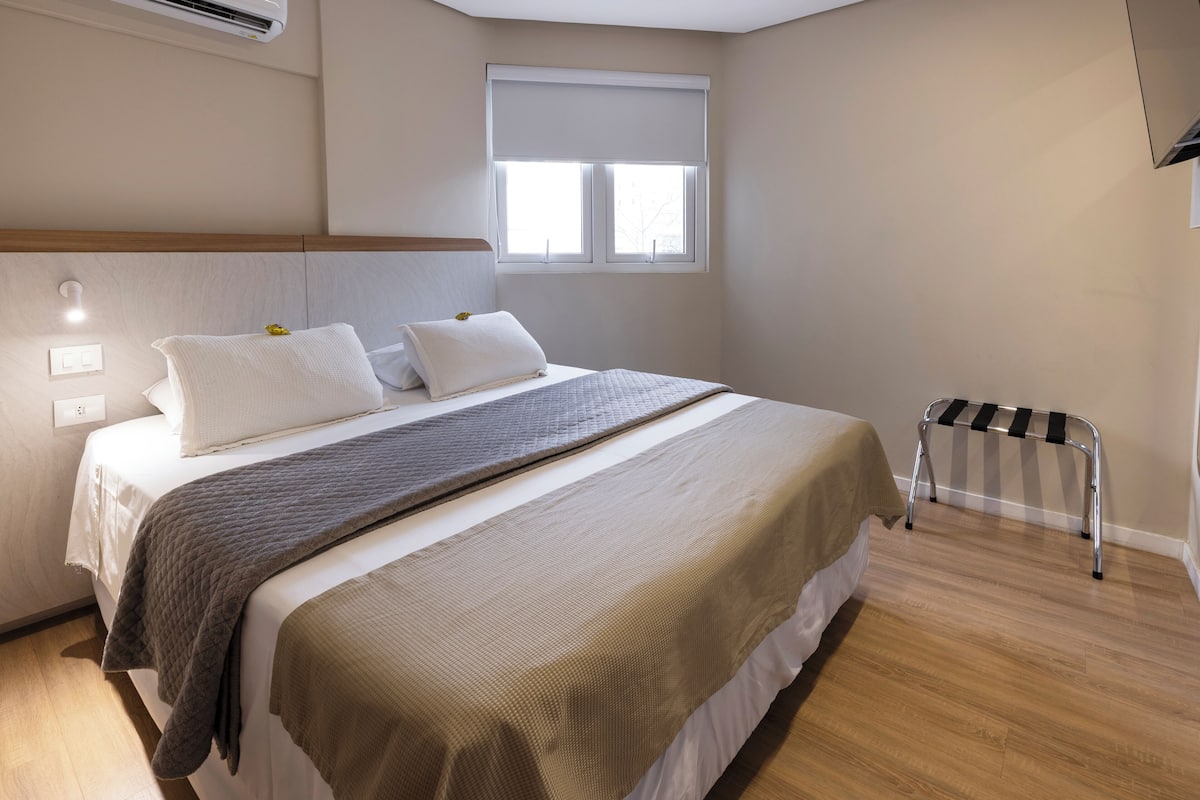A bedroom with a bed, bedside table, window, and radiator.