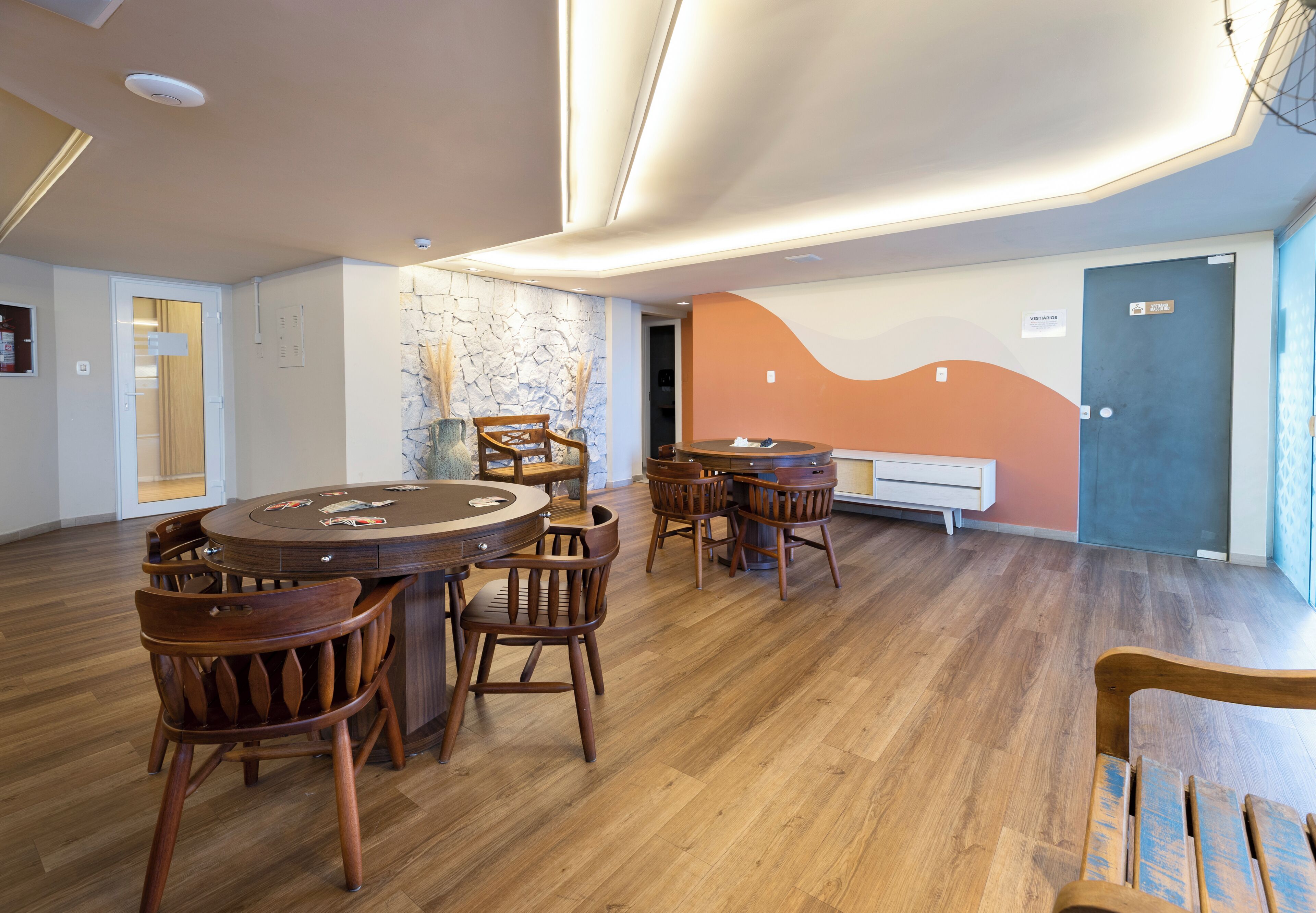 Une pièce spacieuse avec une table ronde en bois et des chaises, un mur en pierre et un design moderne au niveau du plafond.