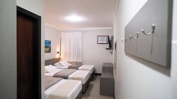 A hotel room with three beds, a television, and a coat rack.