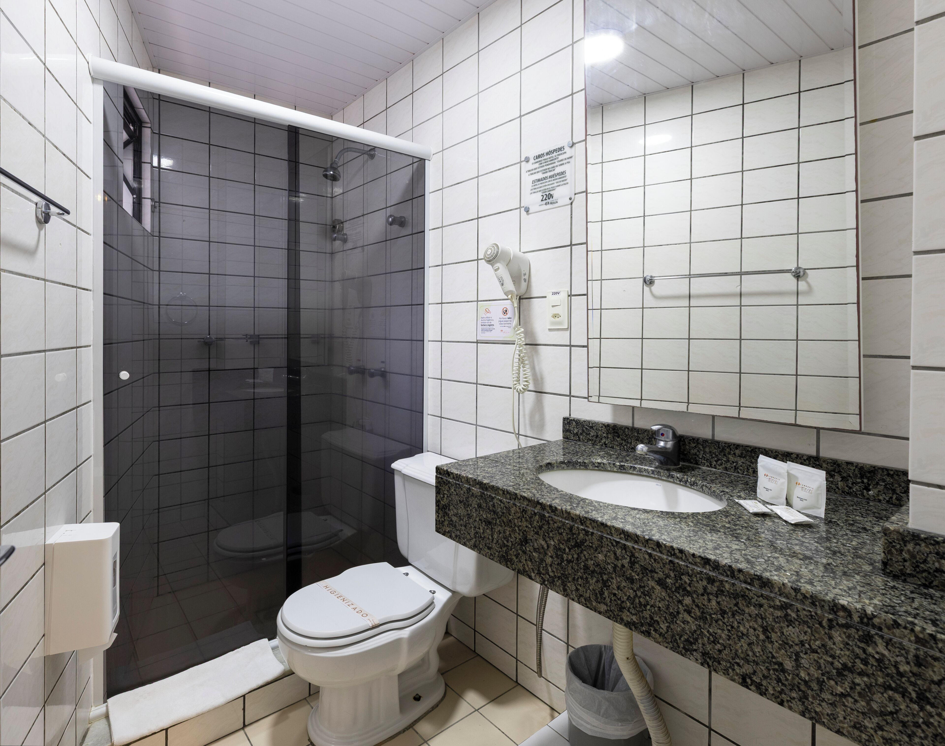 Une salle de bain dotée d’une douche à parois de verre, de toilettes, d’un lavabo avec un plan de travail en granit et d’un miroir au-dessus du lavabo.