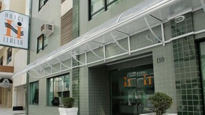 A modern hotel entrance with a glass door, a signboard, and a covered walkway. - Hotel Itália (Balneário Camboriú)