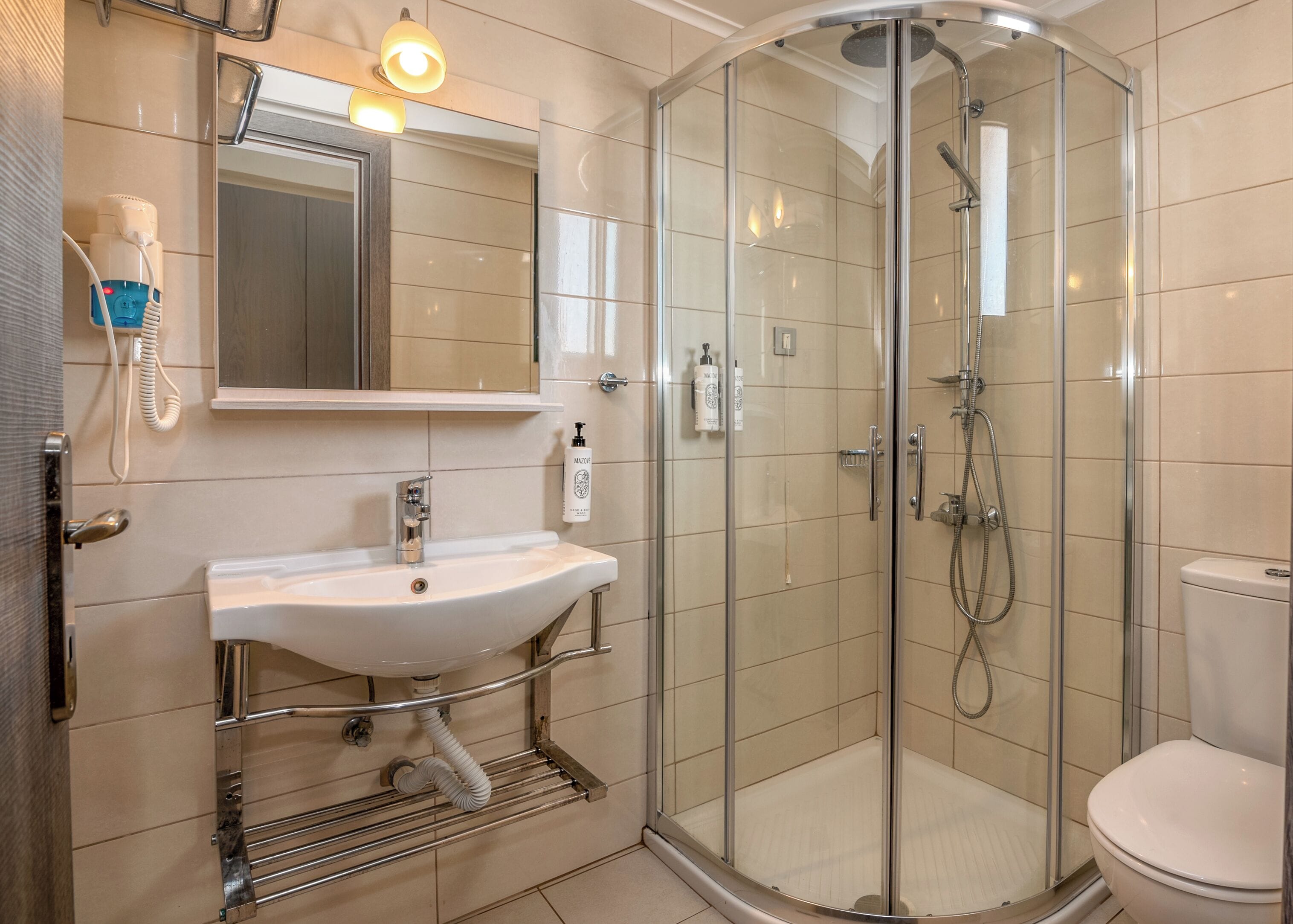 A modern bathroom with a glass-enclosed shower, a white sink with a mirror above it, and a toilet.