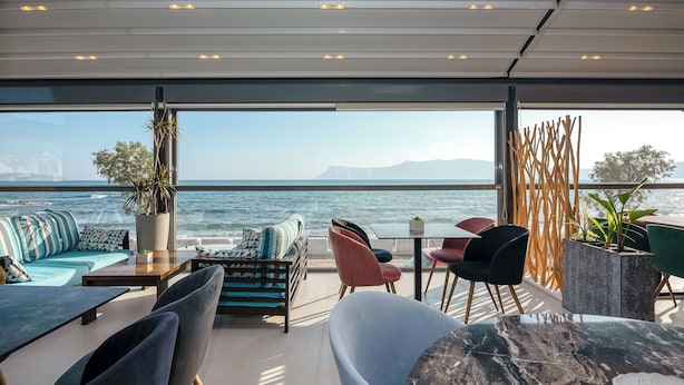 Ett modernt utomhusområde med sittplatser och utsikt över havet, med en soffa, stolar och ett bord.