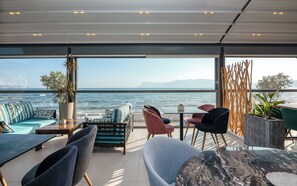 Un espacio de descanso al aire libre y moderno con vistas al mar, que incluye un sofá, sillas y una mesa.
