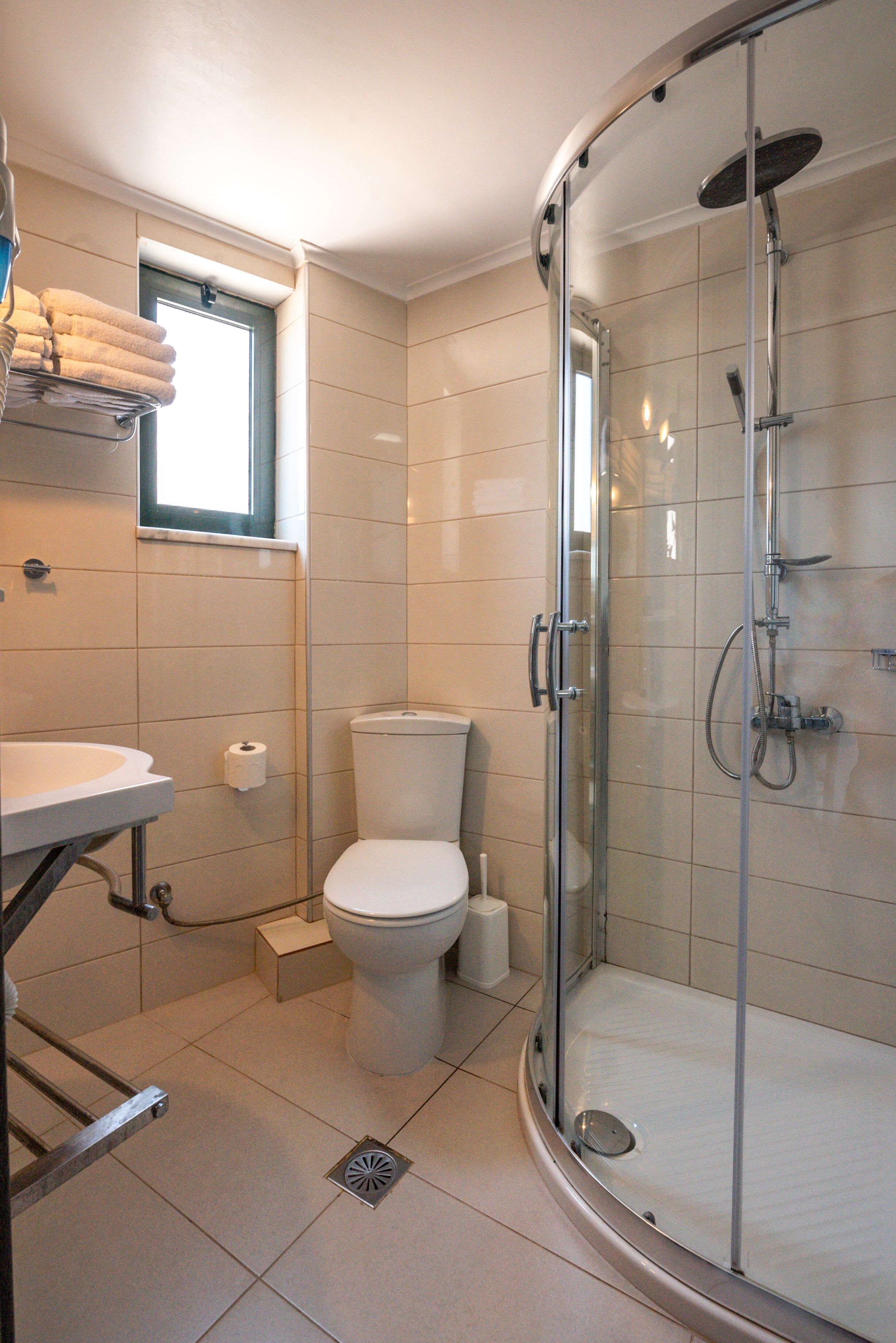 A modern bathroom with a glass-enclosed shower, a toilet, a sink, and a towel rack.