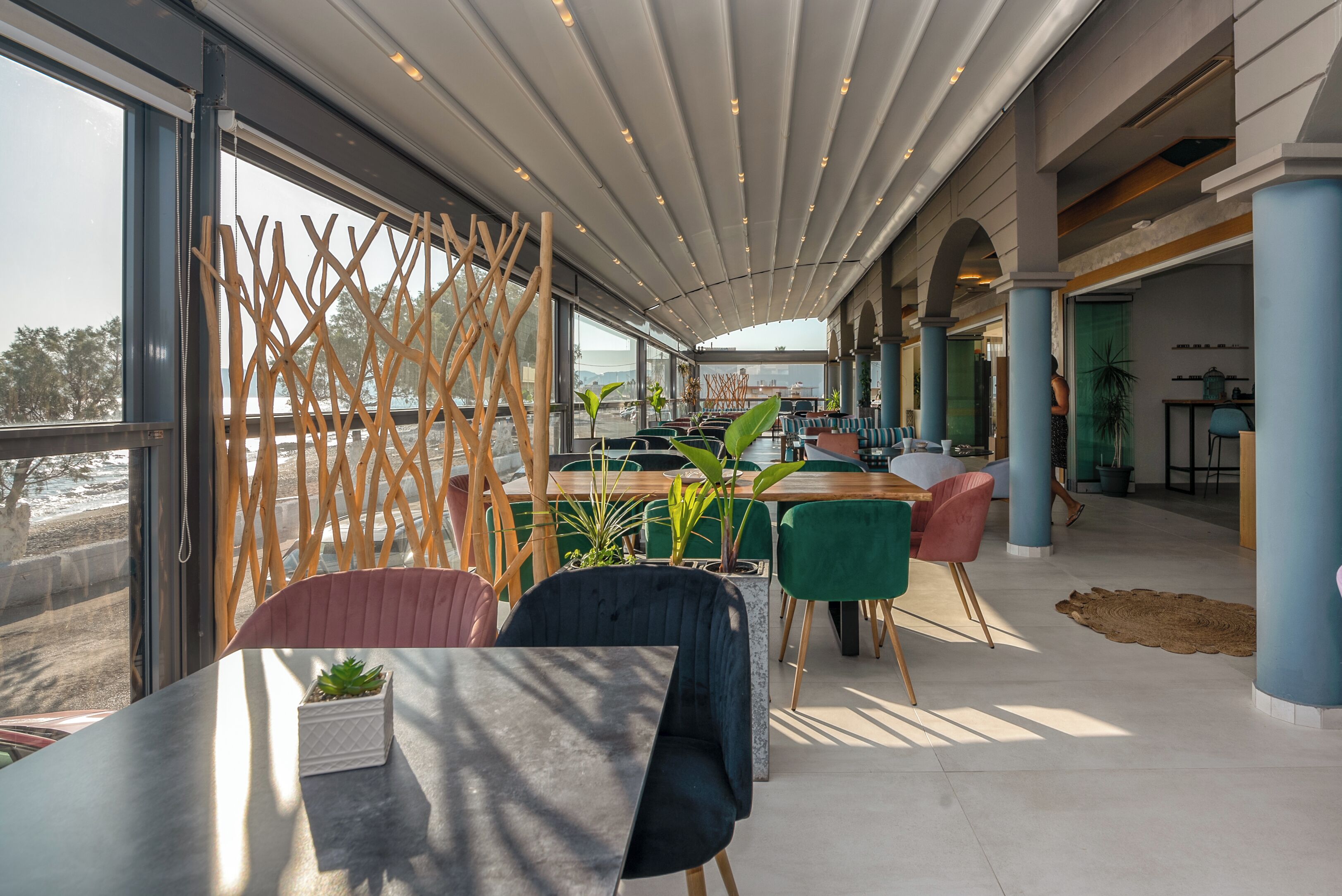 Un espace de restauration moderne, doté d’un haut plafond, de grandes fenêtres et offrant une vue sur l’extérieur.