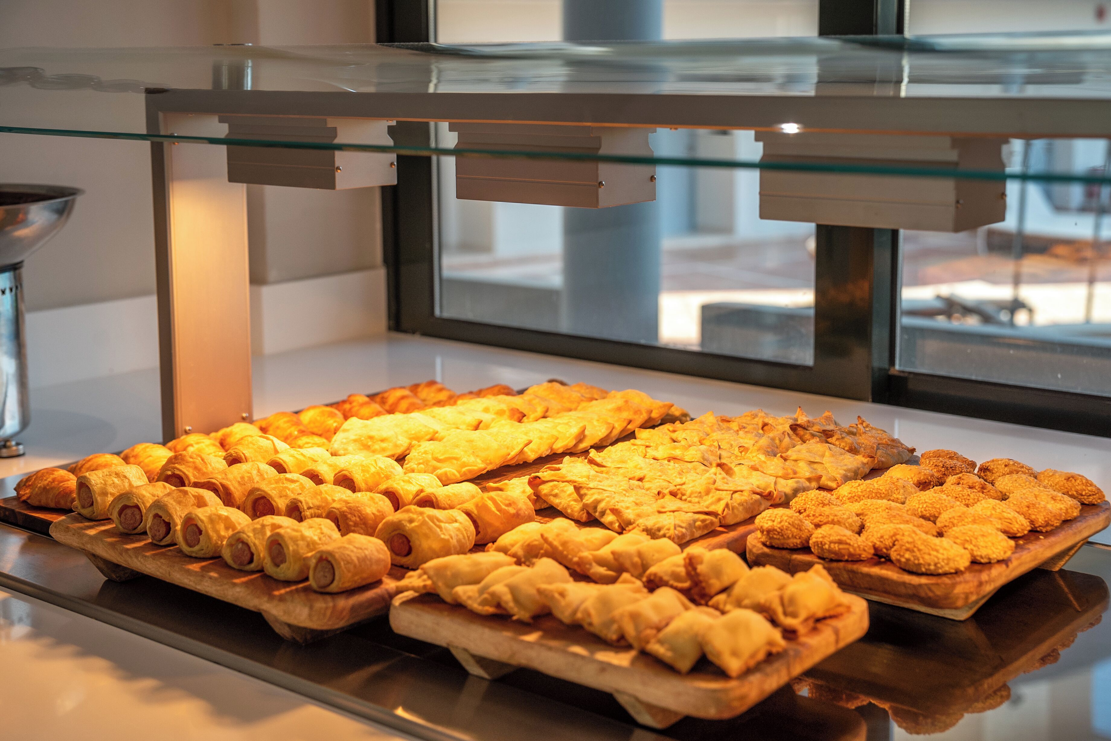A display case with various baked goods, including pastries and bread, in a commercial setting.