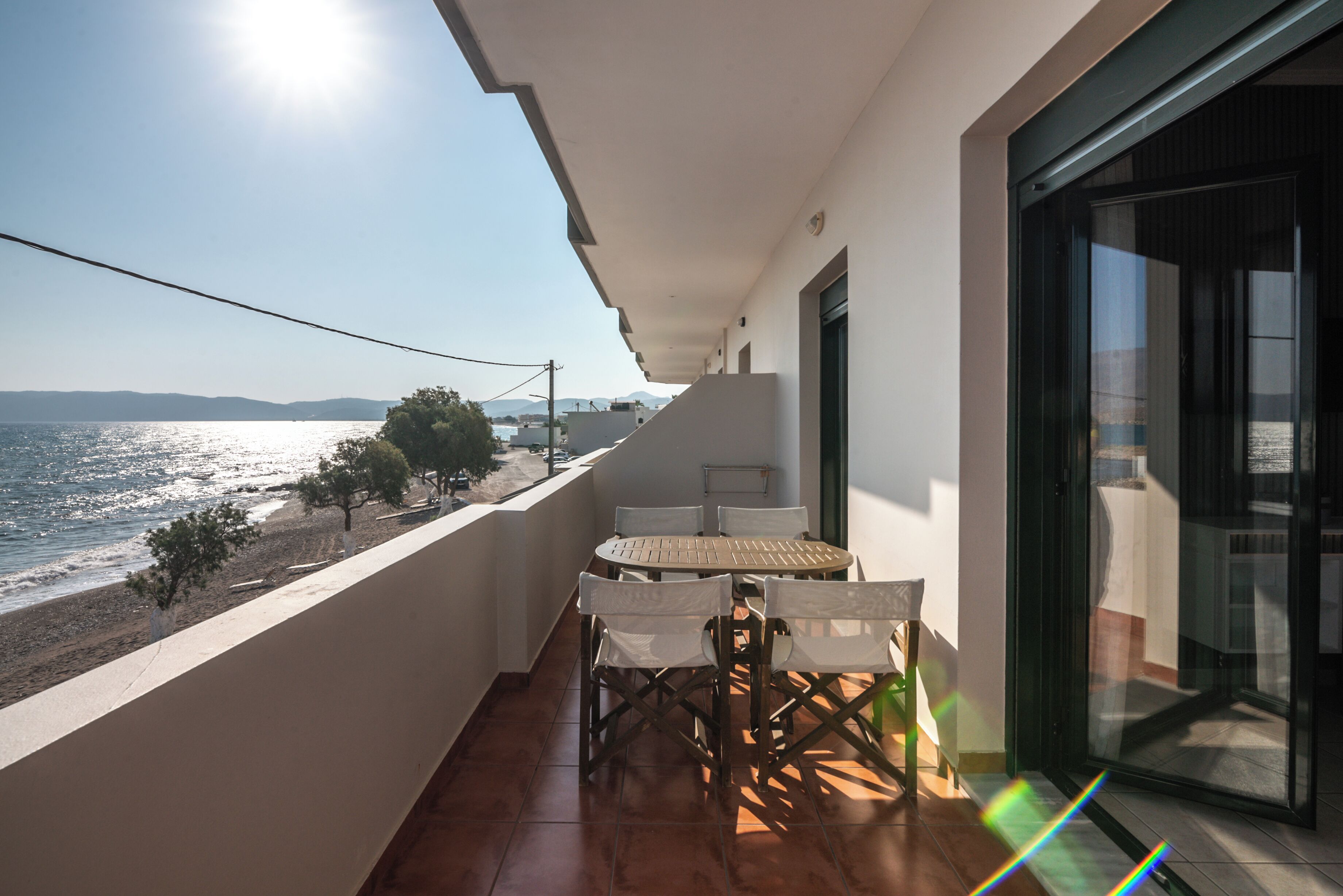 A balcony with a table and chairs overlooking a beach.