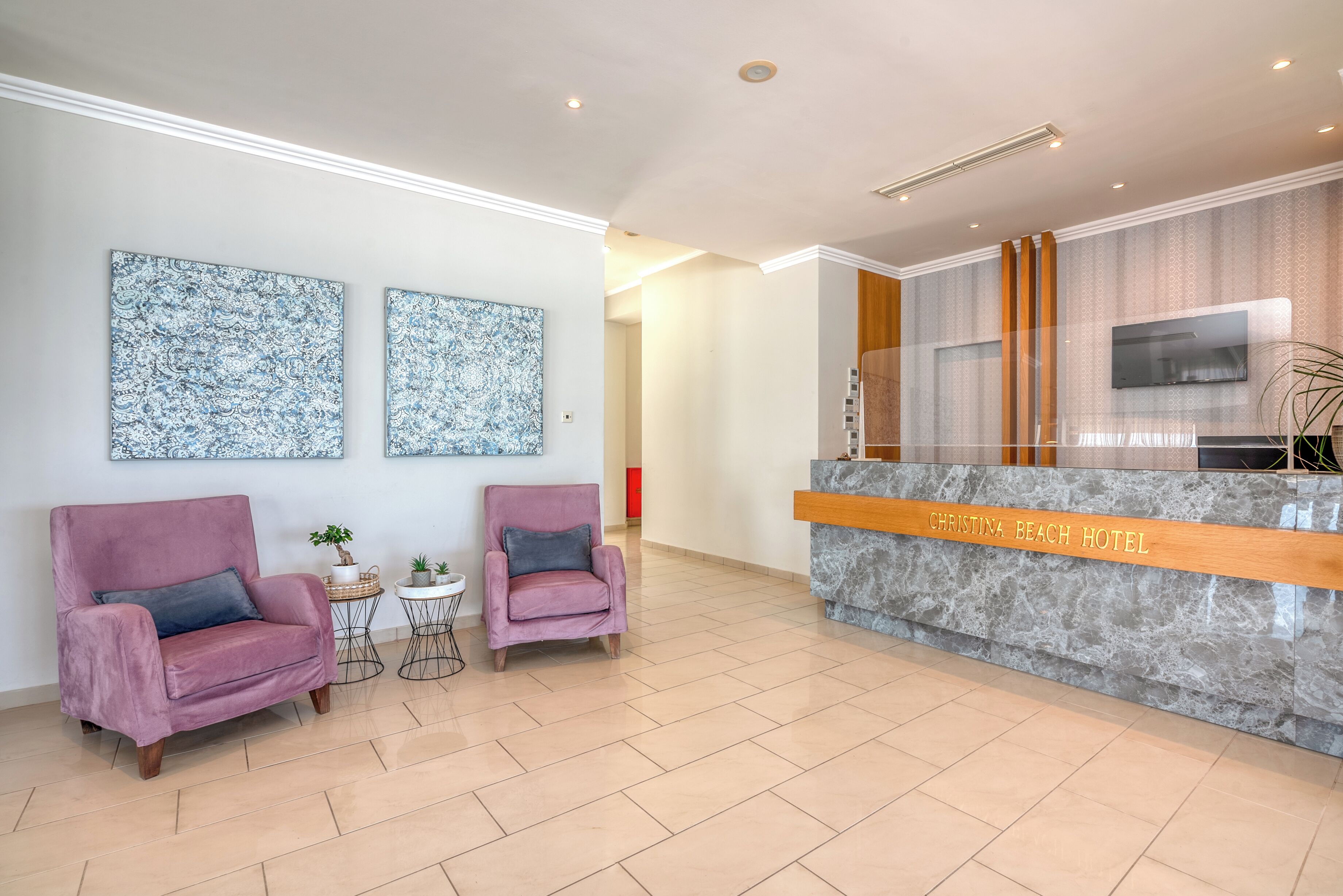A reception area with a marble counter, two plush armchairs, and two abstract wall art pieces.