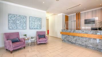 A reception area with a marble counter, two plush armchairs, and two abstract wall art pieces.