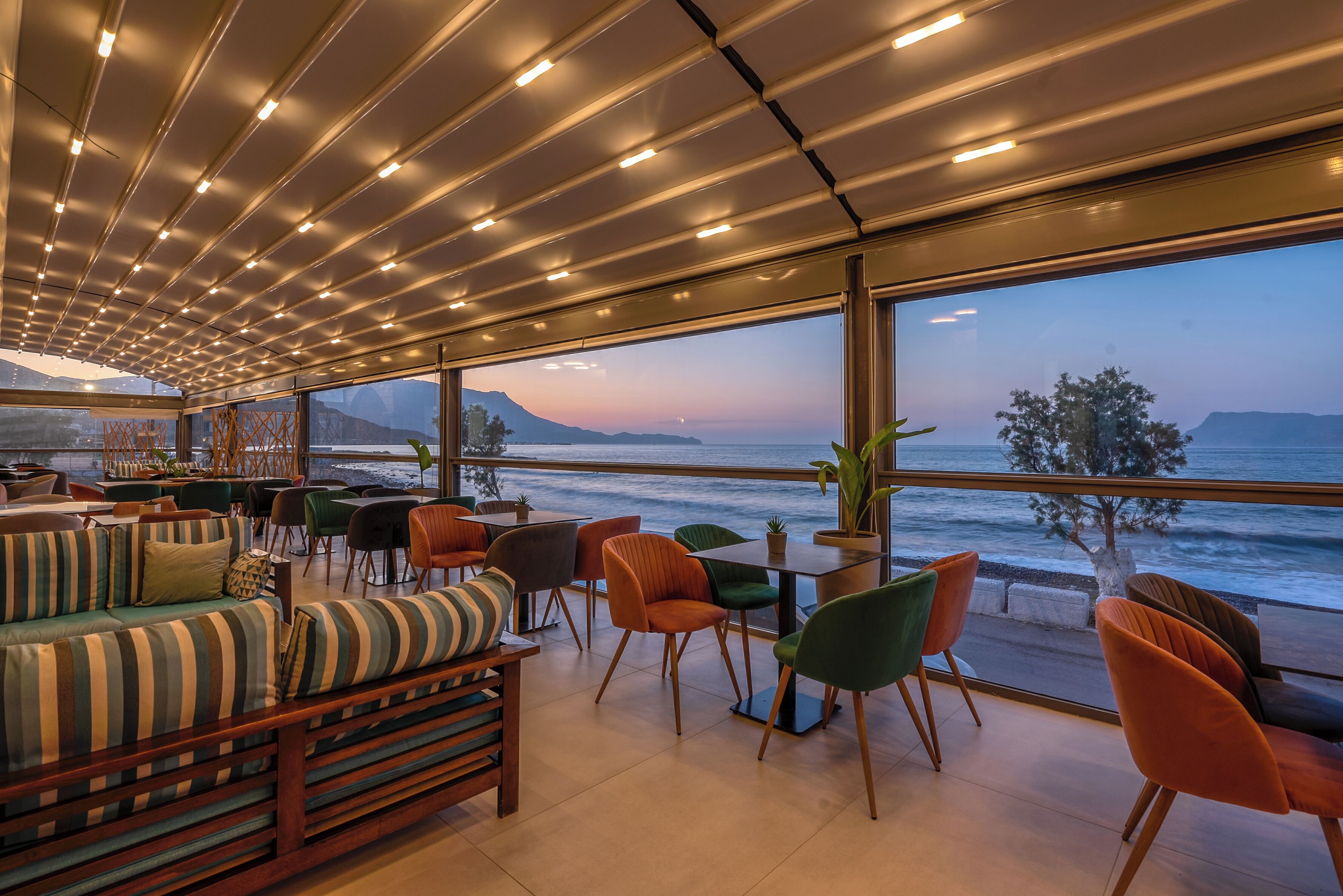 A modern lounge with a view of the ocean, featuring a sofa, chairs, and a table.