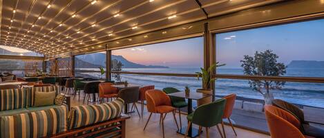 A modern lounge with a view of the ocean, featuring a sofa, chairs, and a table.