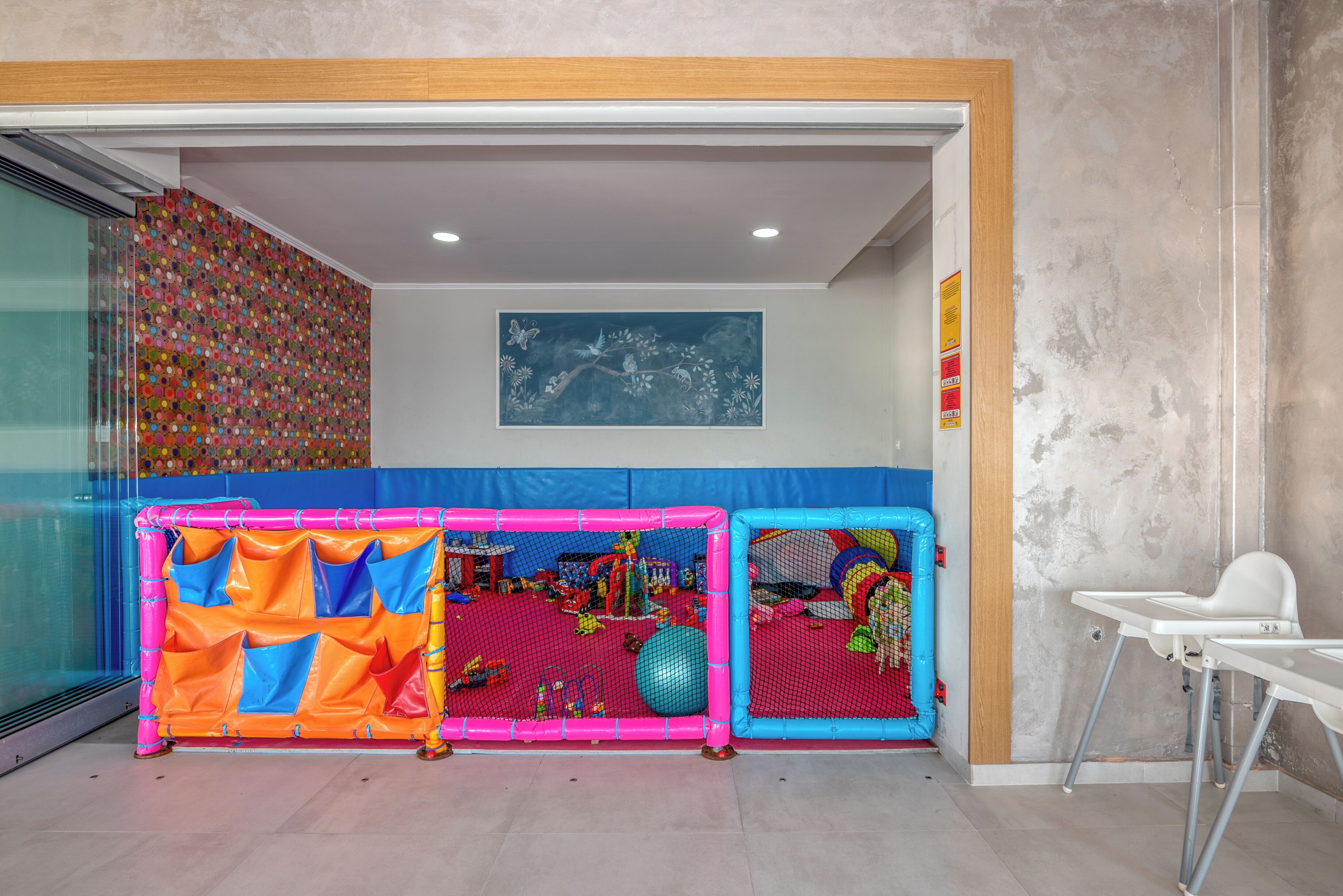 Un área de juegos con paredes acolchadas de colores y un mural en el techo.