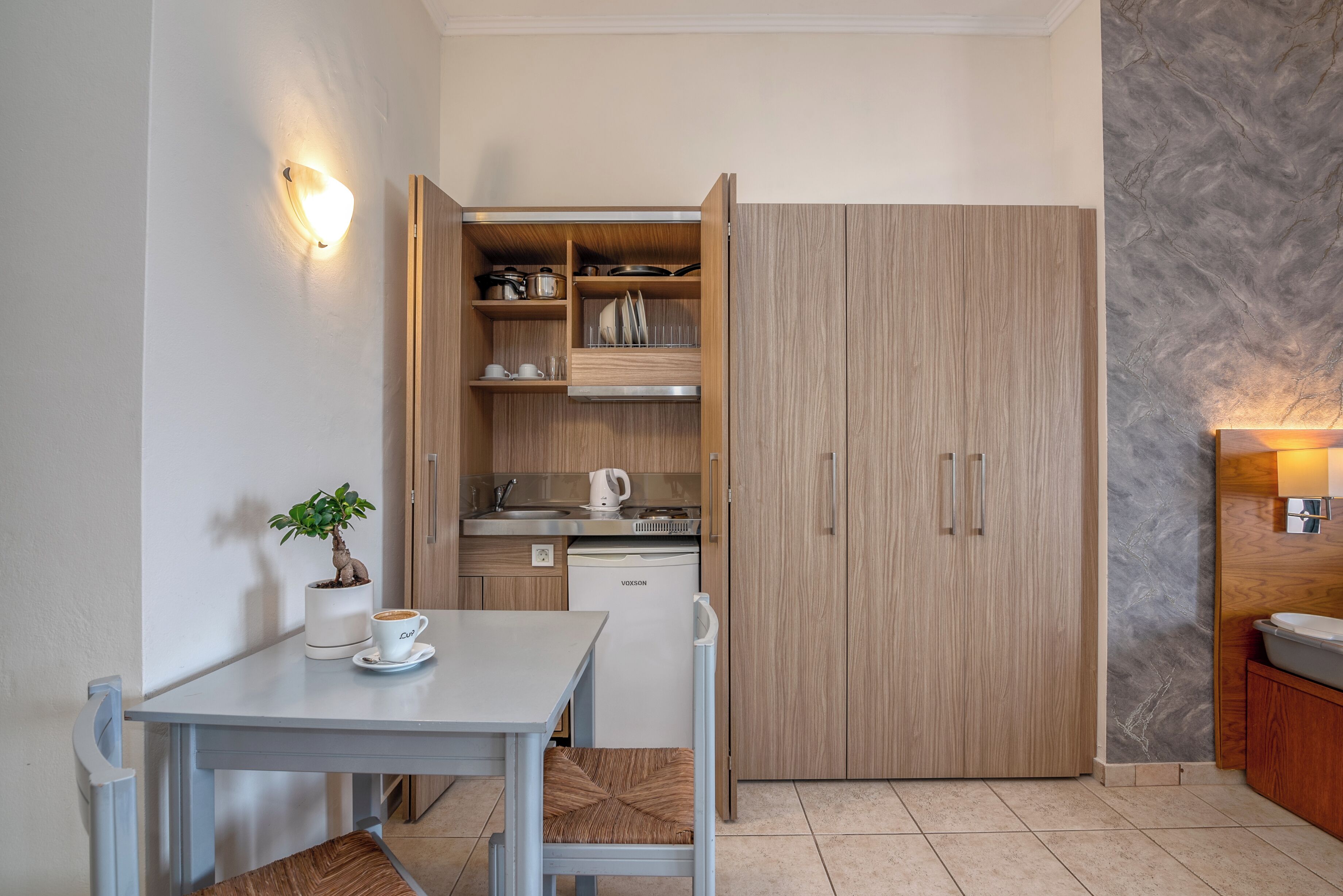 A compact kitchen with wooden cabinets, a built-in oven, and a coffee machine.