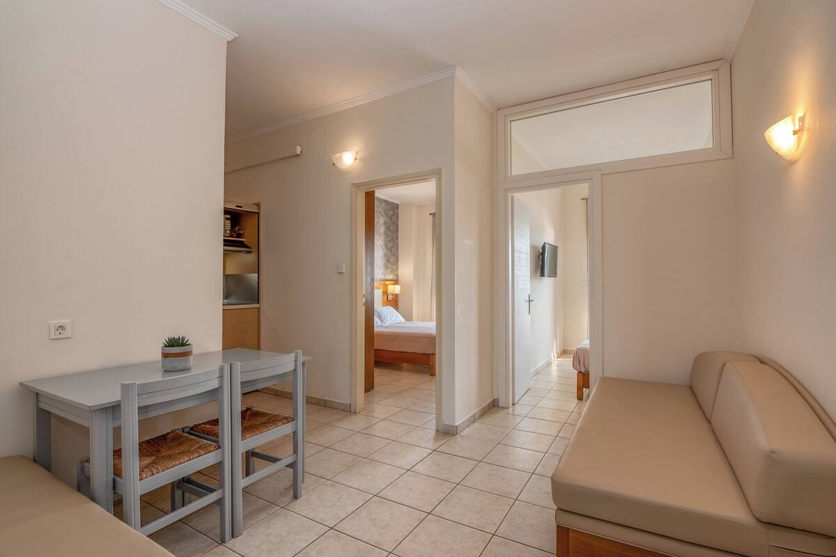 A compact living space with a kitchenette, a dining area, and a bedroom.
