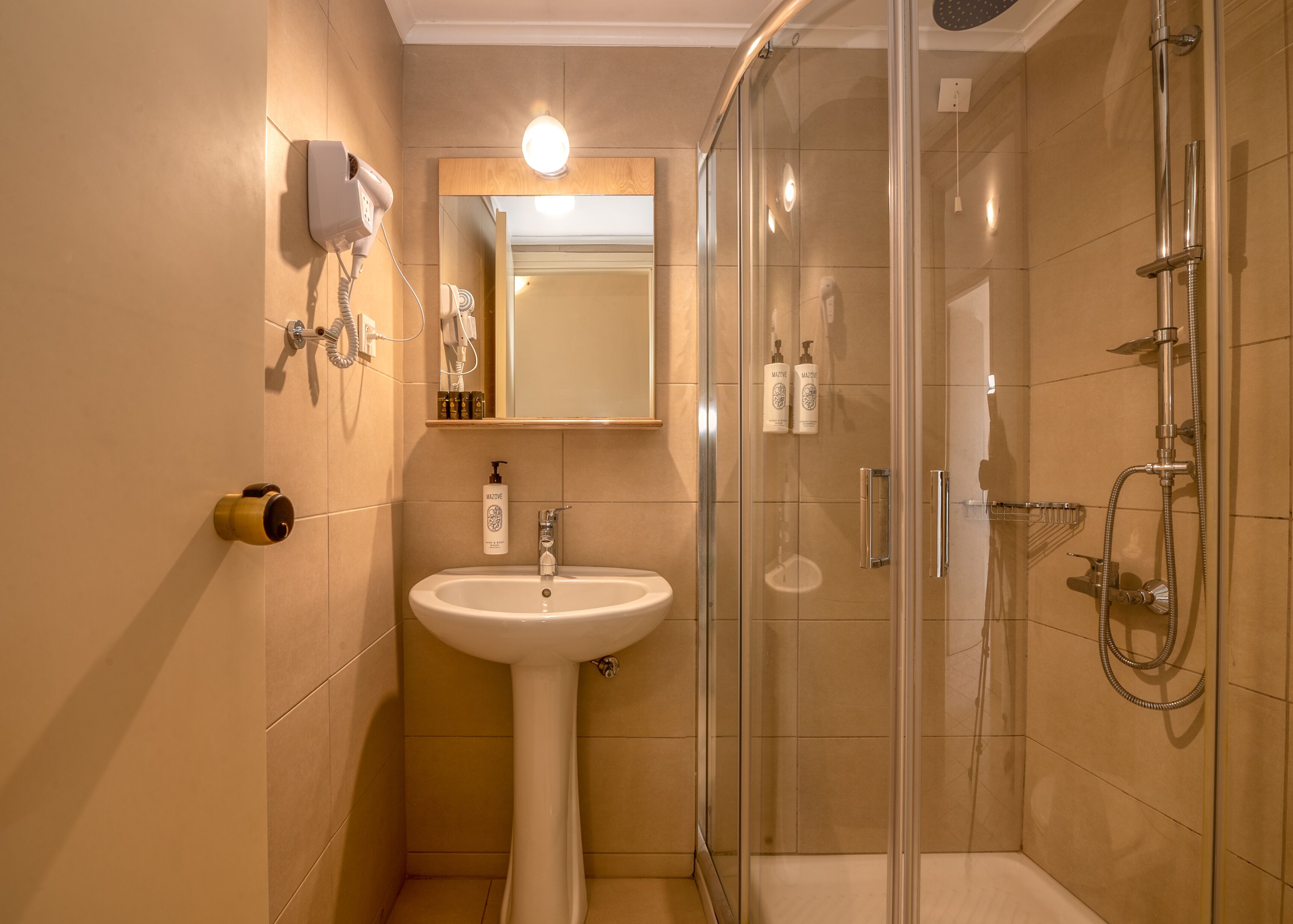 Une salle de bain moderne avec une douche à parois de verre, un lavabo sur colonne et un miroir au-dessus du lavabo.