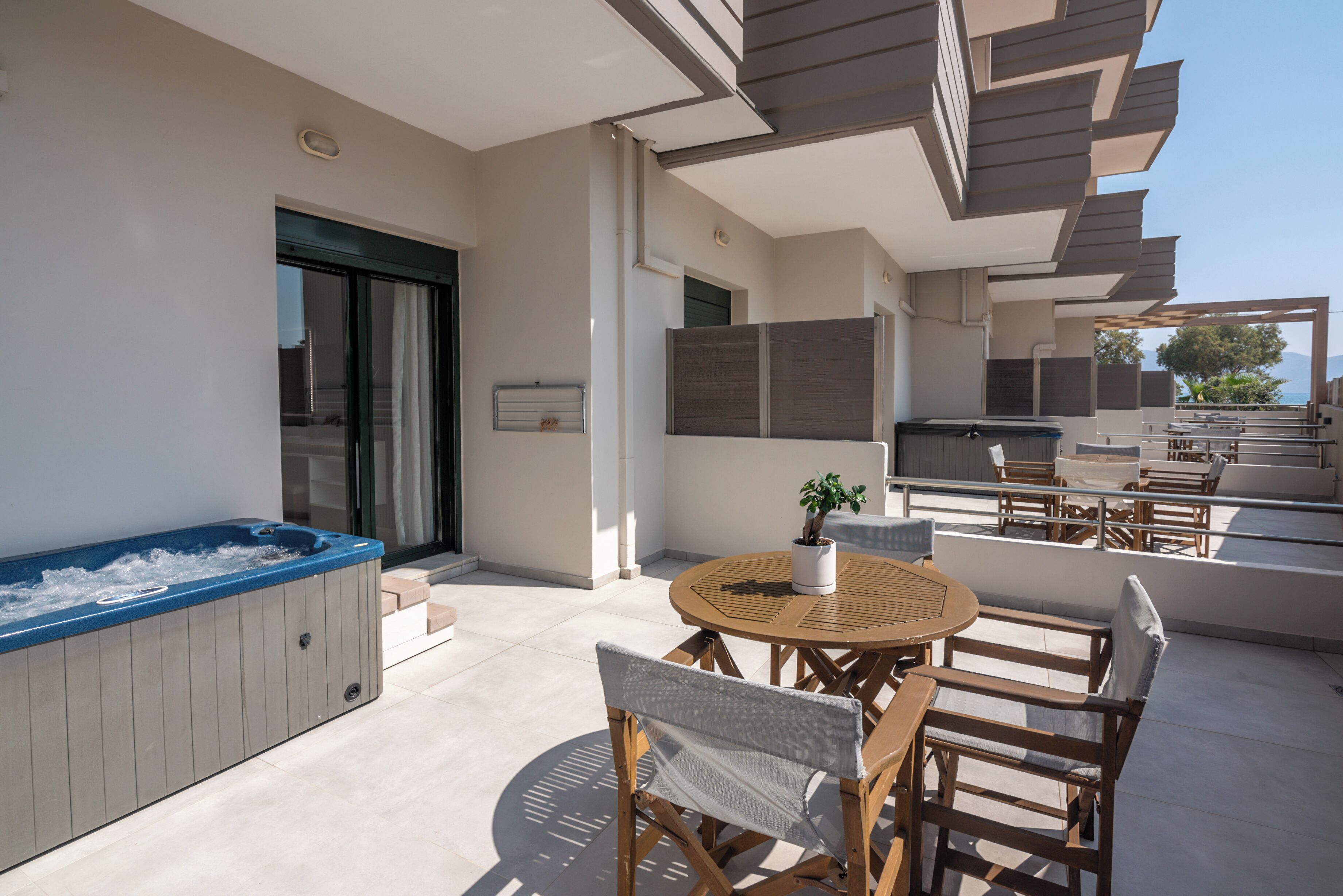 A modern outdoor patio with a hot tub, wooden furniture, and a dining area.