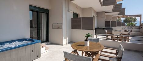 A modern outdoor patio with a hot tub, wooden furniture, and a dining area.