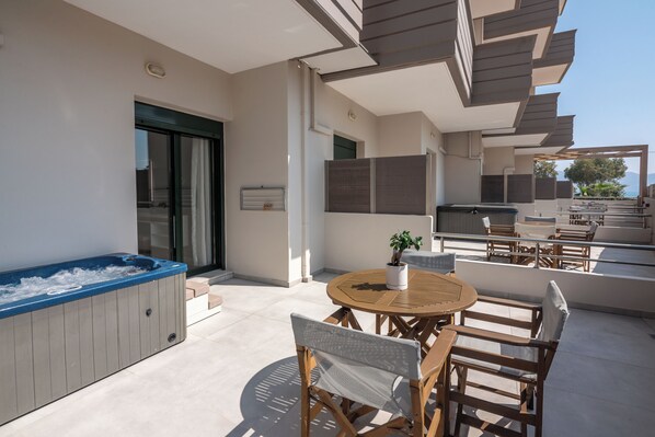 Un patio exterior moderno con jacuzzi, mobiliario de madera y zona de comedor.