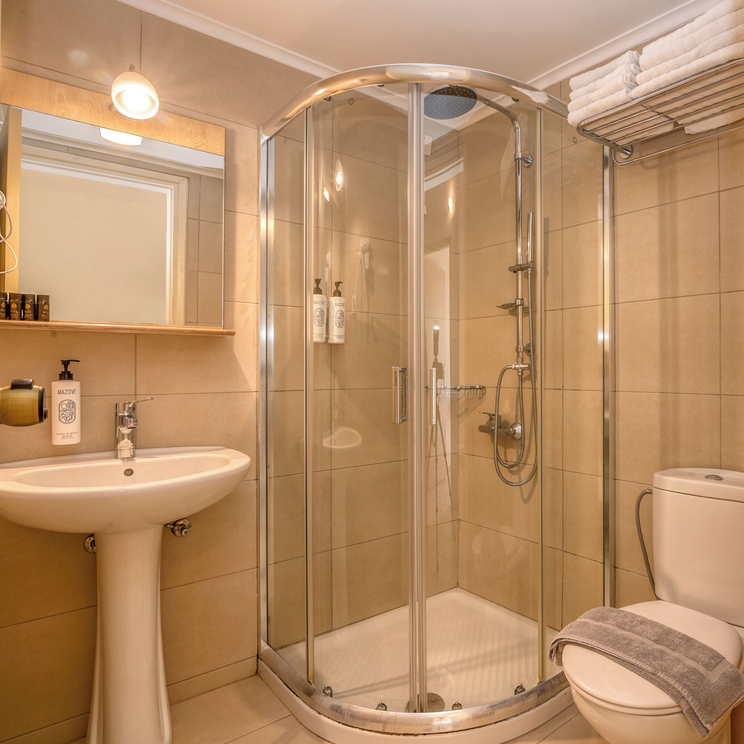 A modern bathroom with a glass-enclosed shower, a pedestal sink, and a toilet.