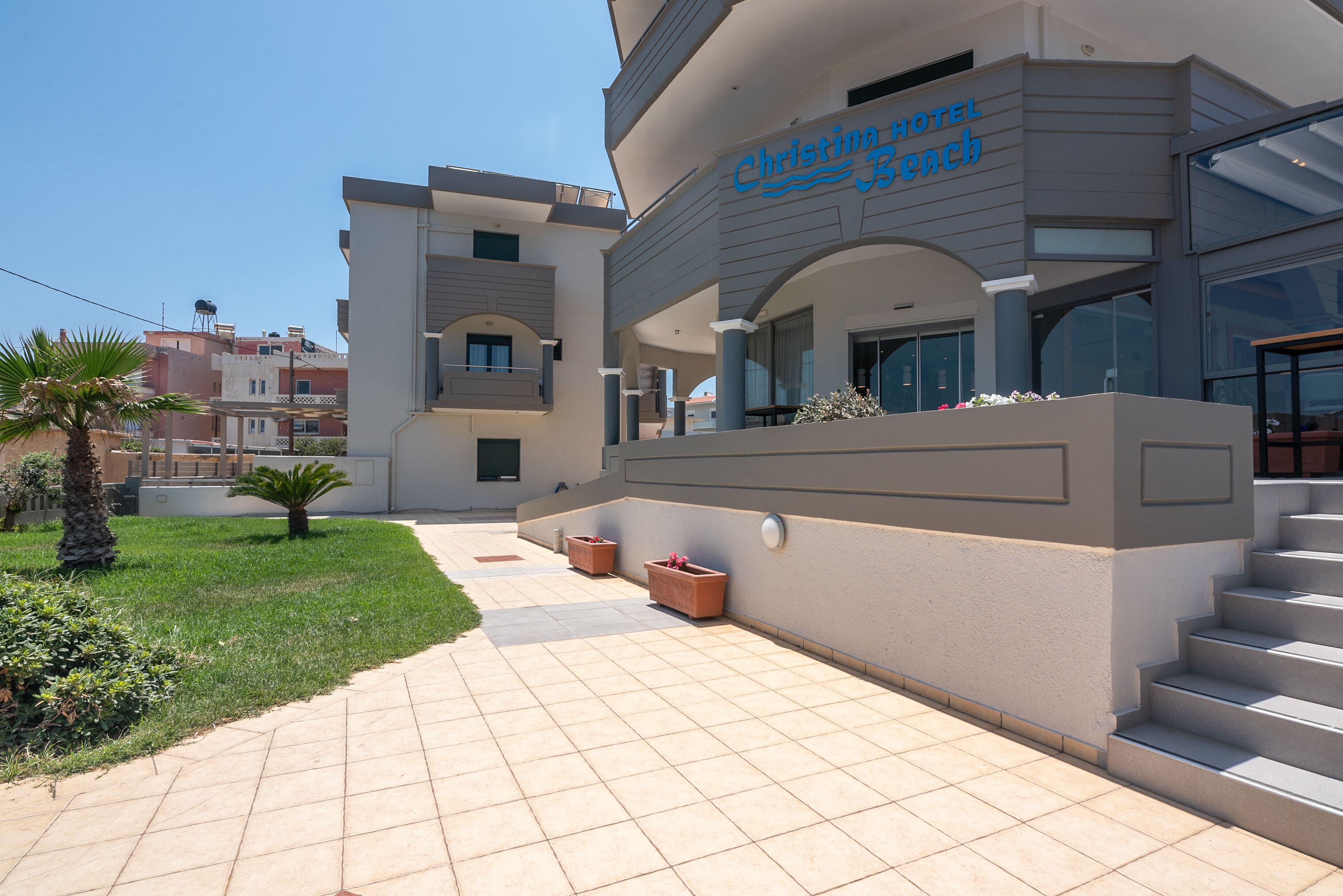 Un hotel moderno con un letrero con su nombre, un área exterior cubierta y una escalera que conduce a la entrada.