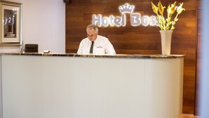 Un mostrador de recepción en Hotel Boss con un fondo de madera y un cartel.