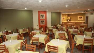 Een restaurant met meerdere tafels en stoelen, ingericht in een ruime opstelling.